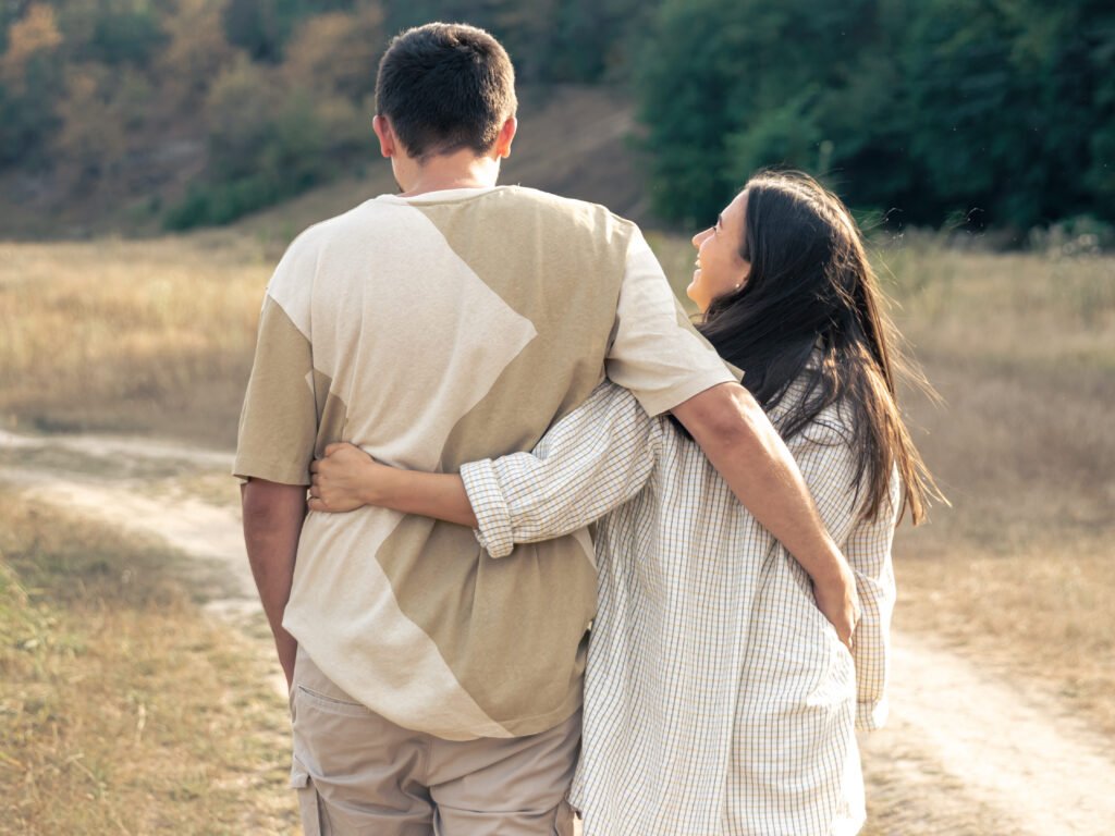 A man and a woman are walking in a field, a happy couple.